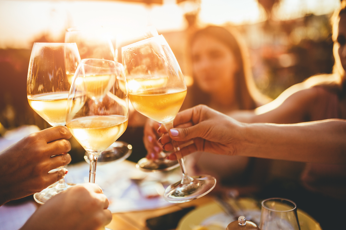 People clinking glasses with wine on the summer terrace of cafe or restaurant